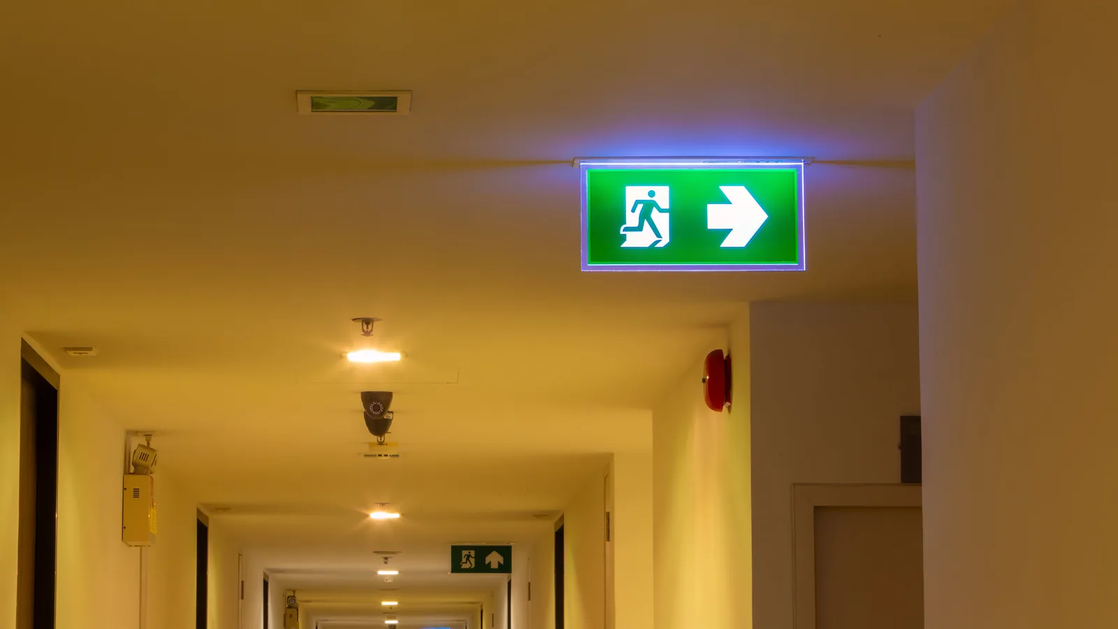 Podświetlony znak wyjścia ewakuacyjnego na korytarzu budynku