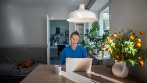 Praca na laptopie przy stole w domu — stanowisko komputerowe poza biurem